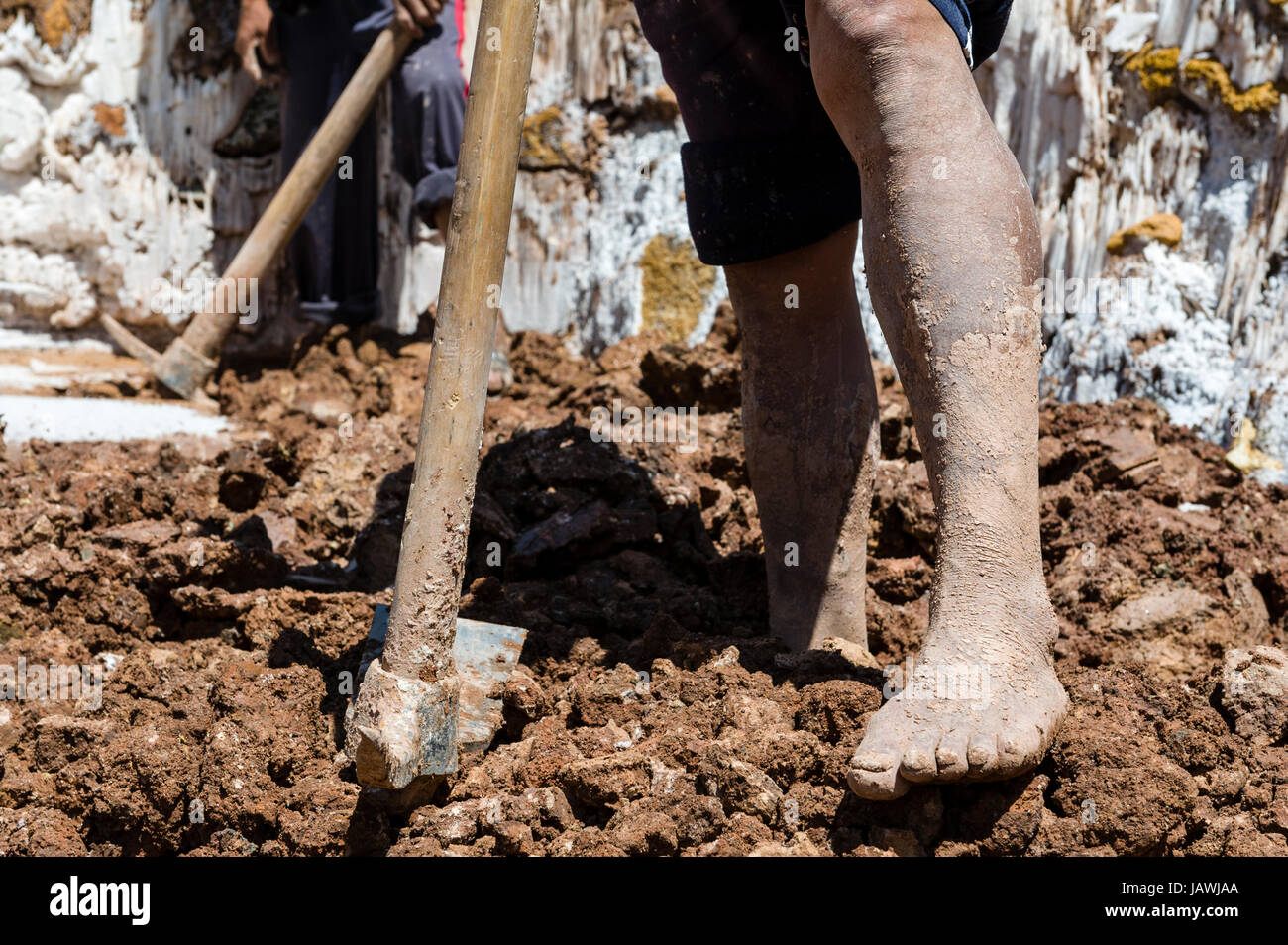 A labourer uses a spade to make salt evaporation ponds in an ancient Inca salt mine. Stock Photo
