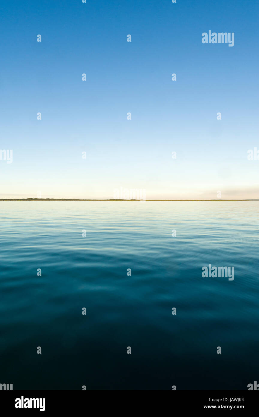 A dead calm ocean surface at twilight. Stock Photo