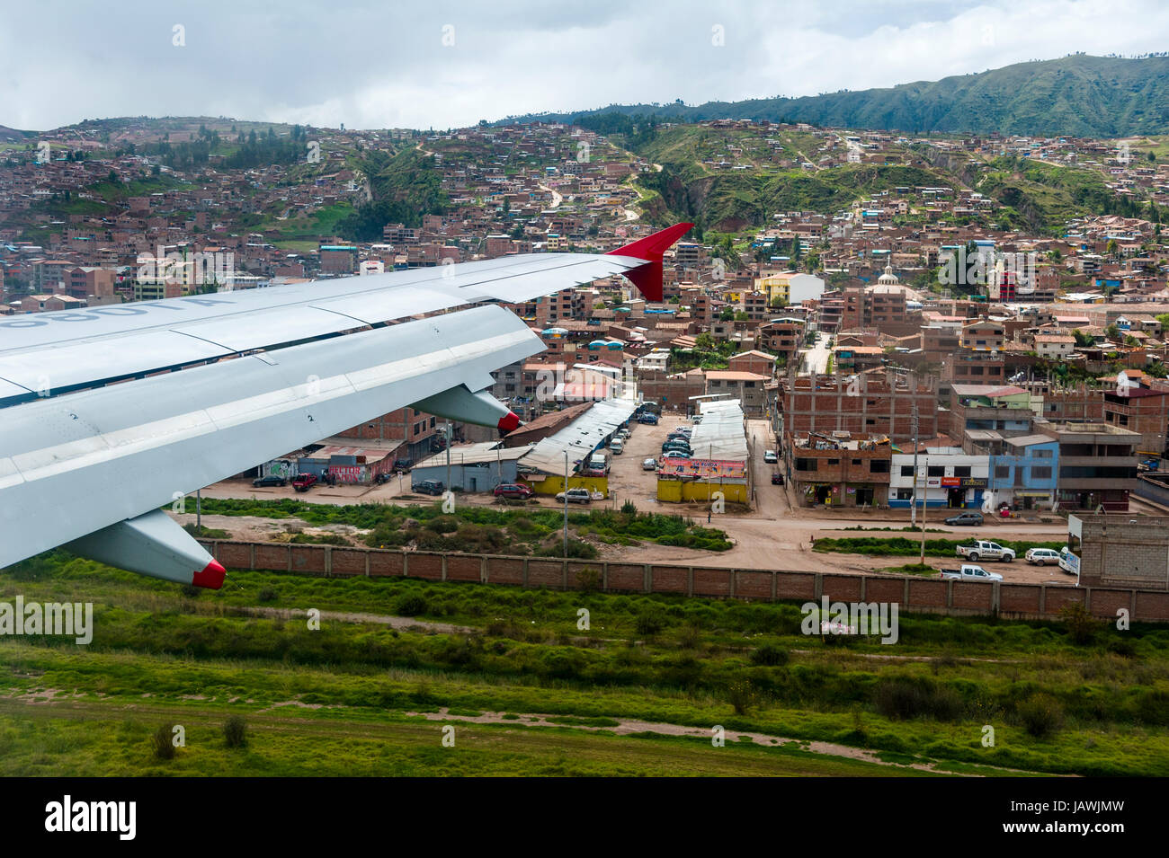 A plane wing flying over an airport and city suburbs in the Andes mountains. Stock Photo