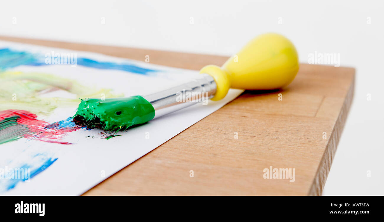 green paint with paint brush  and paper on wooden table Stock Photo