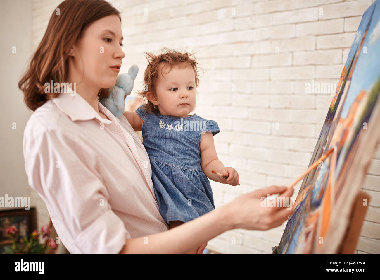 Young Woman Painting with Child in Art Studio Stock Photo