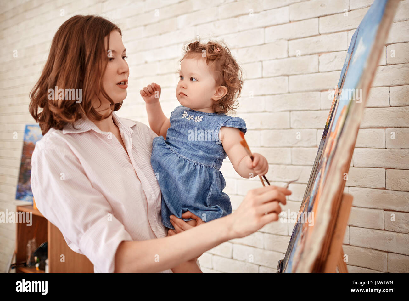 Female Artist Painting In Art Studio with Little Child Stock Photo