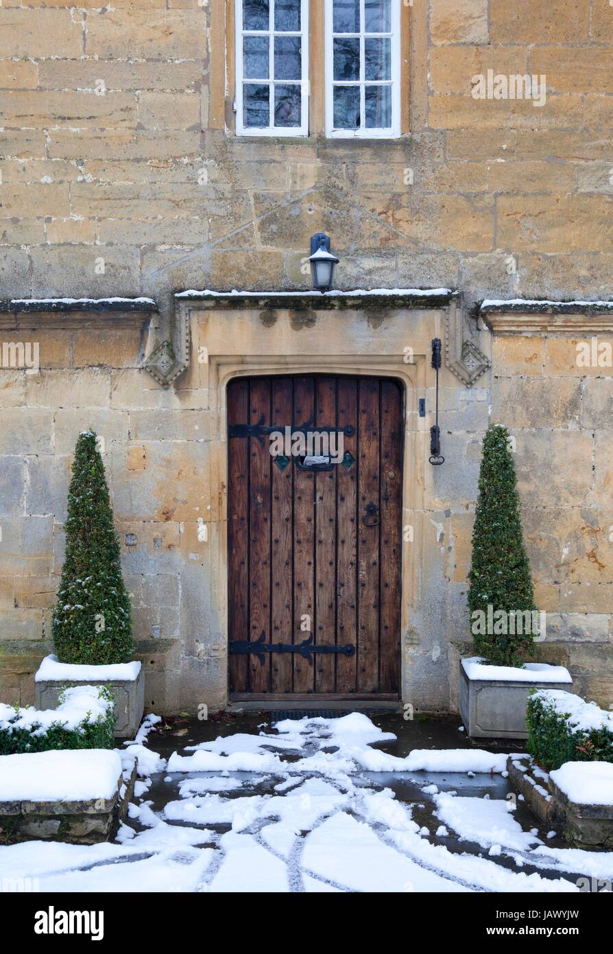 Pretty period property doorway with topiary box trees and snow