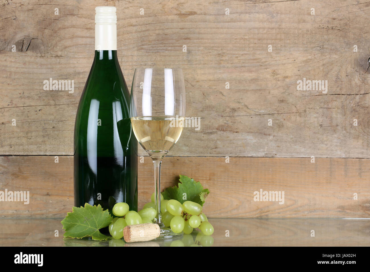 Weißwein in Weinflasche und Weinglas vor einem Hintergrund aus Holz Stock Photo