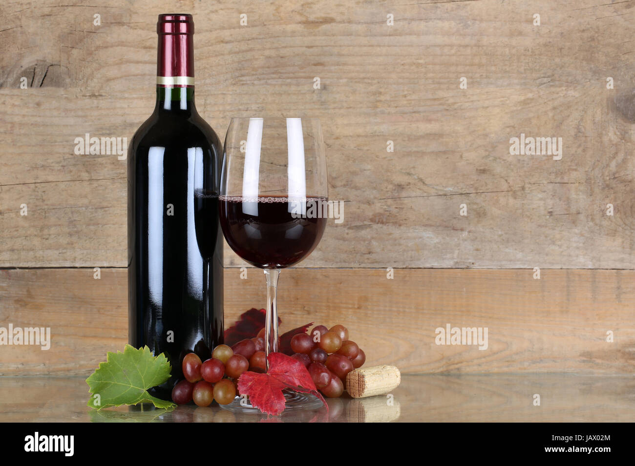 Rotwein in Weinflasche und Weinglas vor einem Hintergrund aus Holz Stock Photo