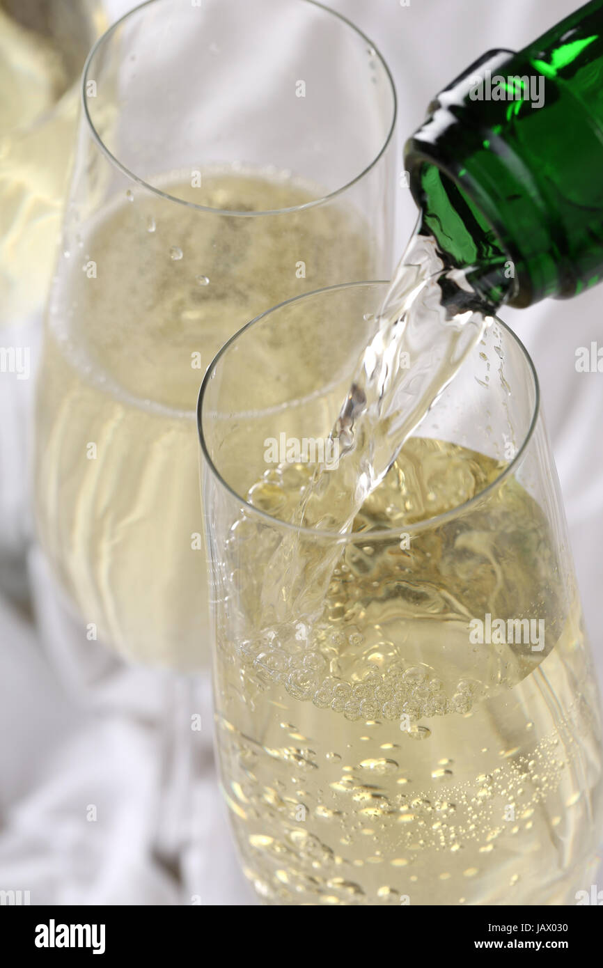 Sekt wird zum Geburtstag oder Silvester aus einer Sektflasche in ein Sektglas eingegossen Stock Photo