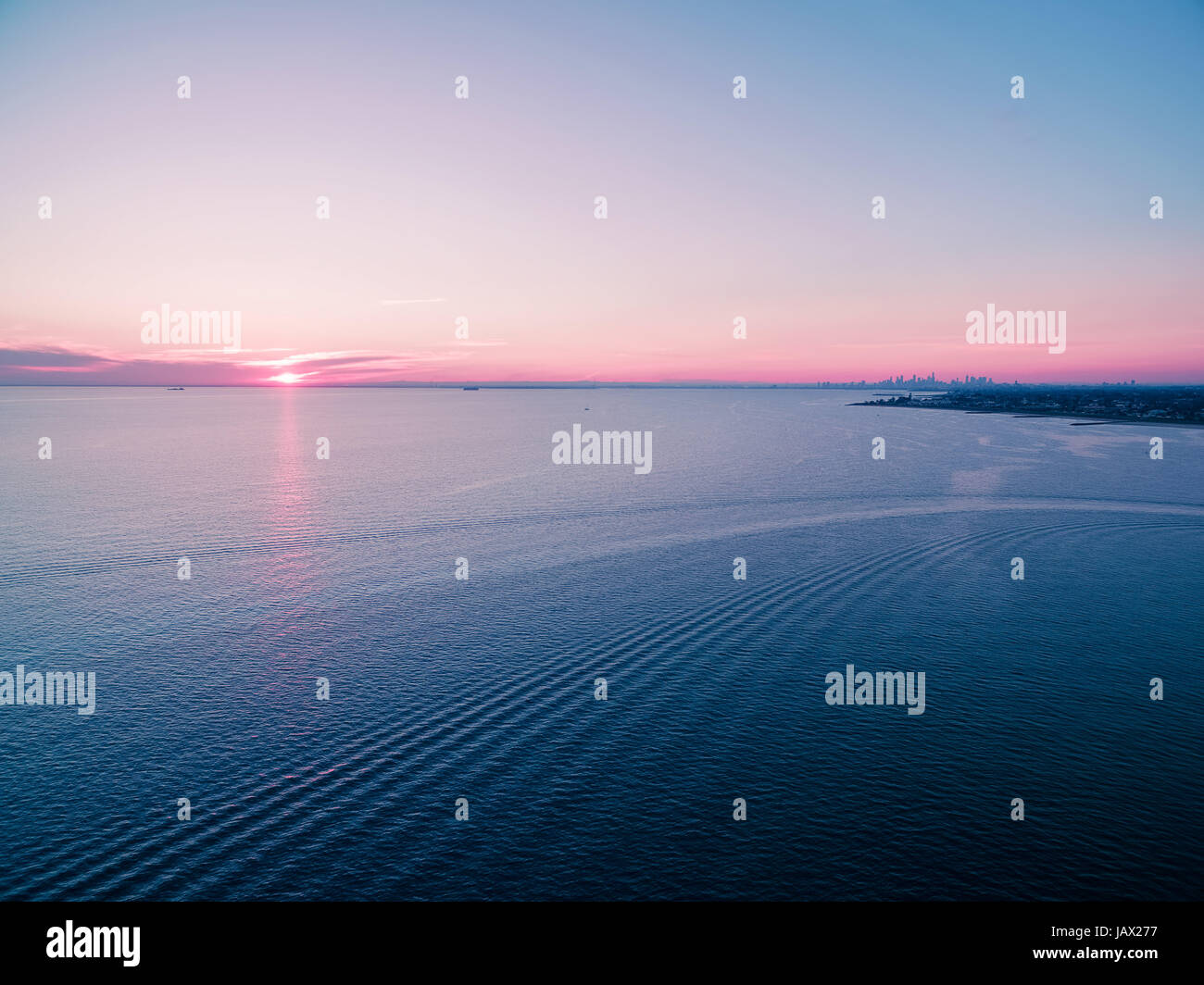 Aerial view of beautiful sunset over water with skyscrapers silhouettes ...