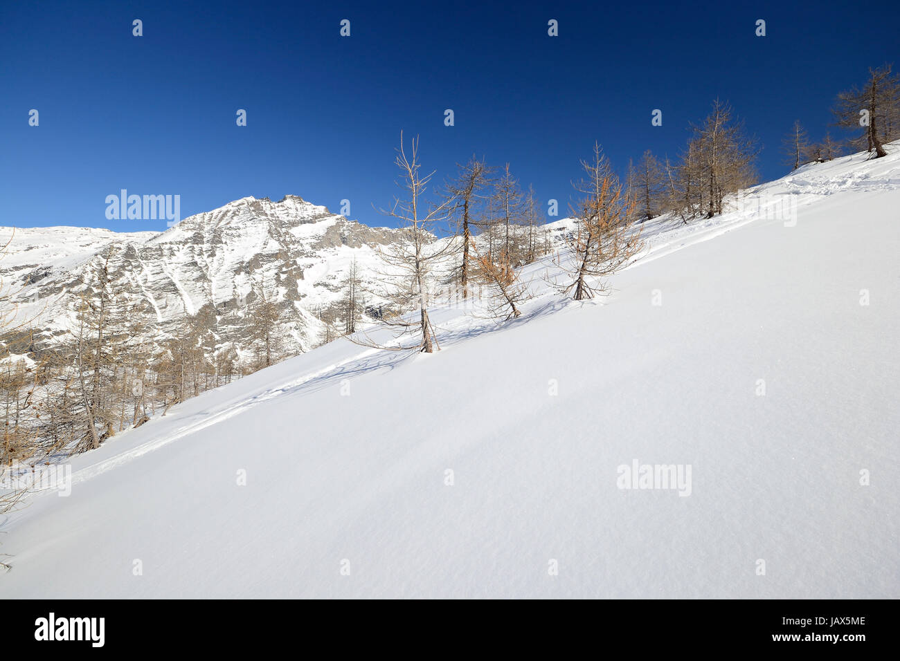 Candid off piste ski slope in scenic background of high mountain peaks ...