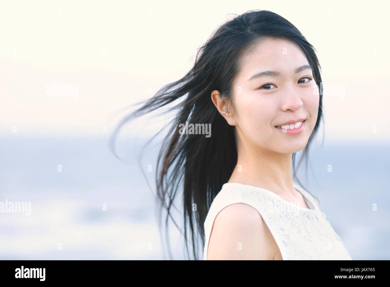 Young Japanese woman in a white dress at a cliff over the sea at ...