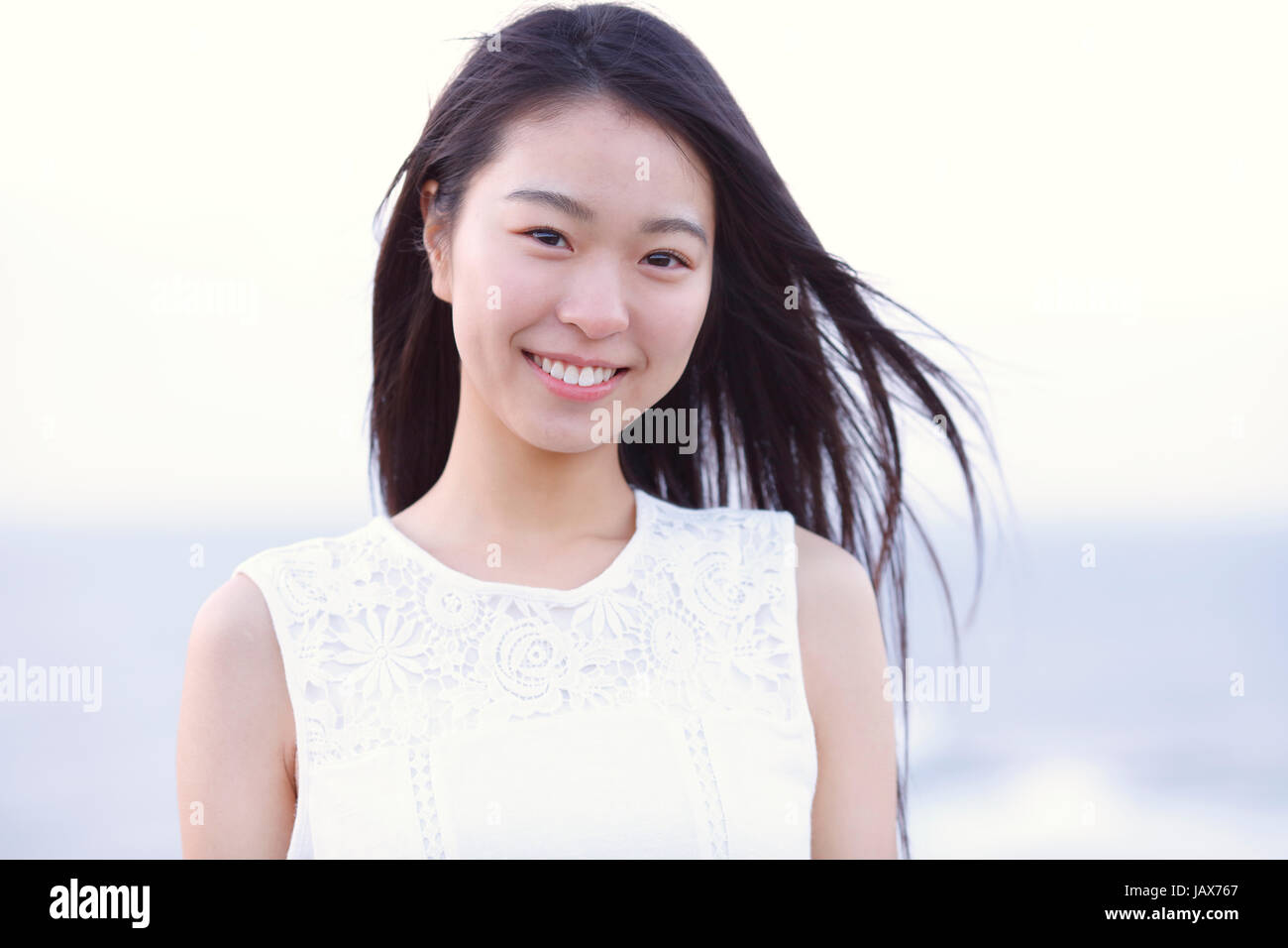 Young Japanese woman in a white dress at a cliff over the sea at ...