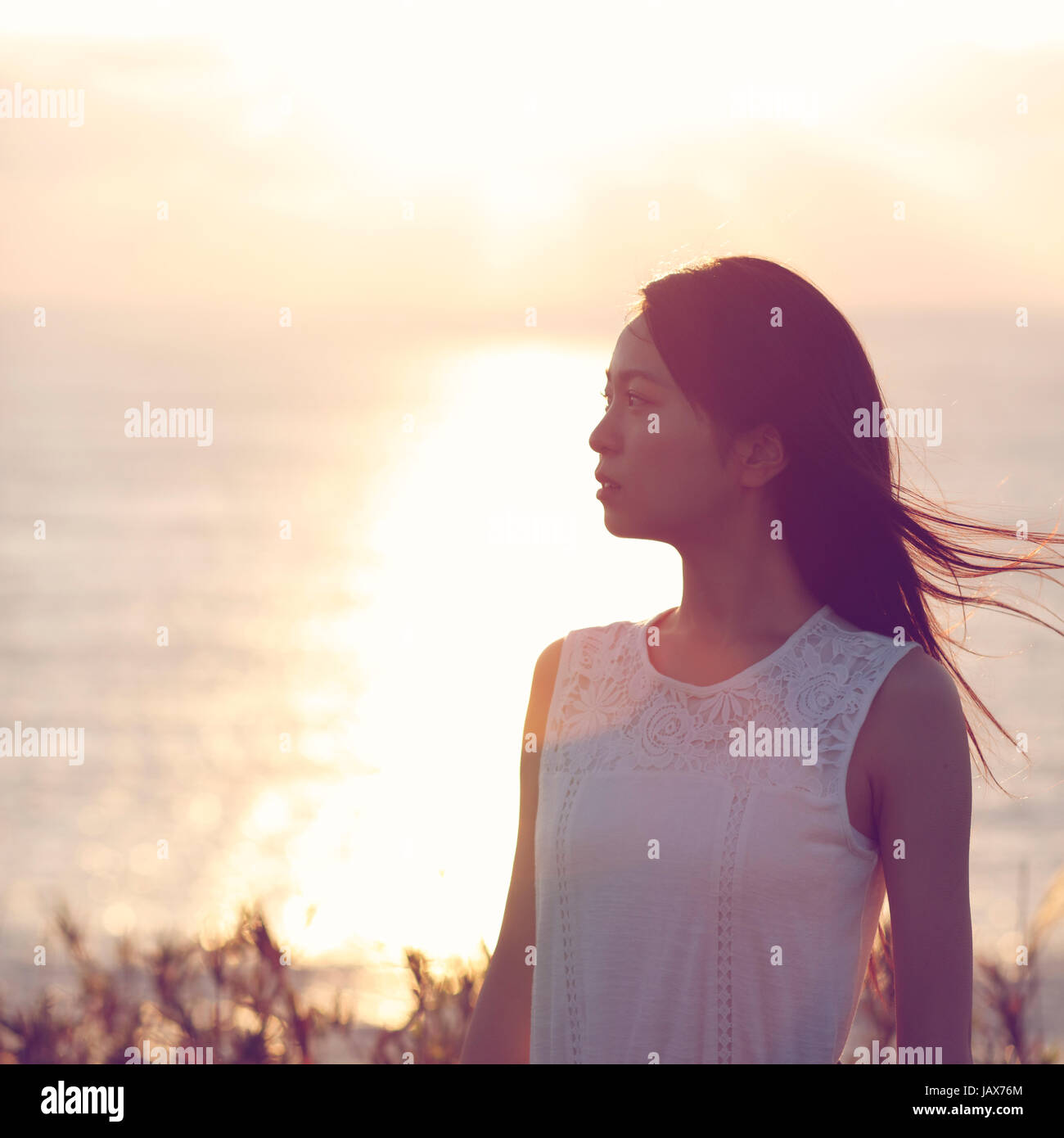 Young Japanese woman in a white dress at a cliff over the sea at ...