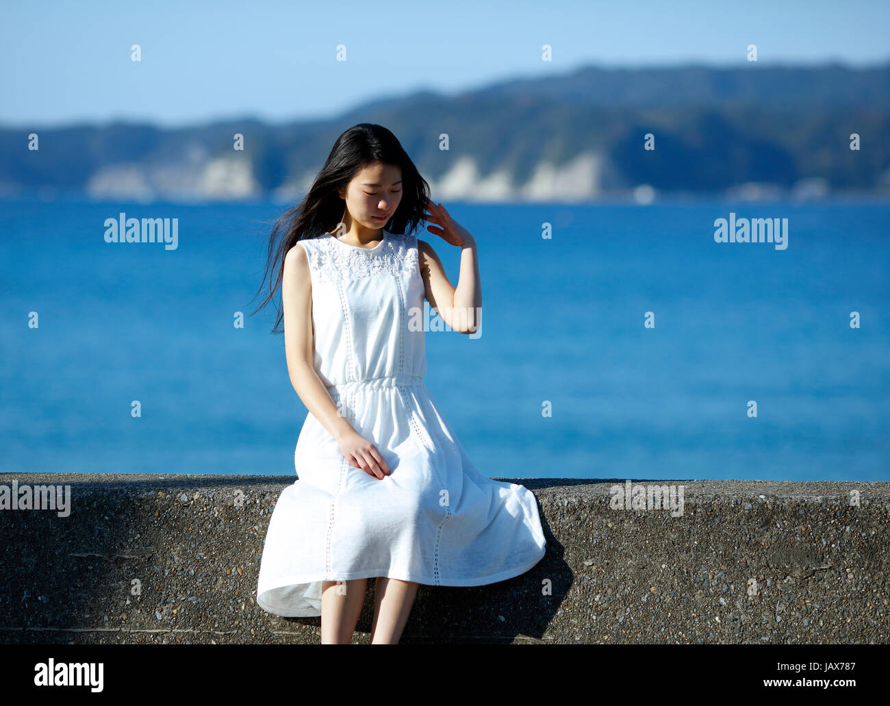 Young Japanese woman in a white dress by the sea, Chiba, Japan Stock