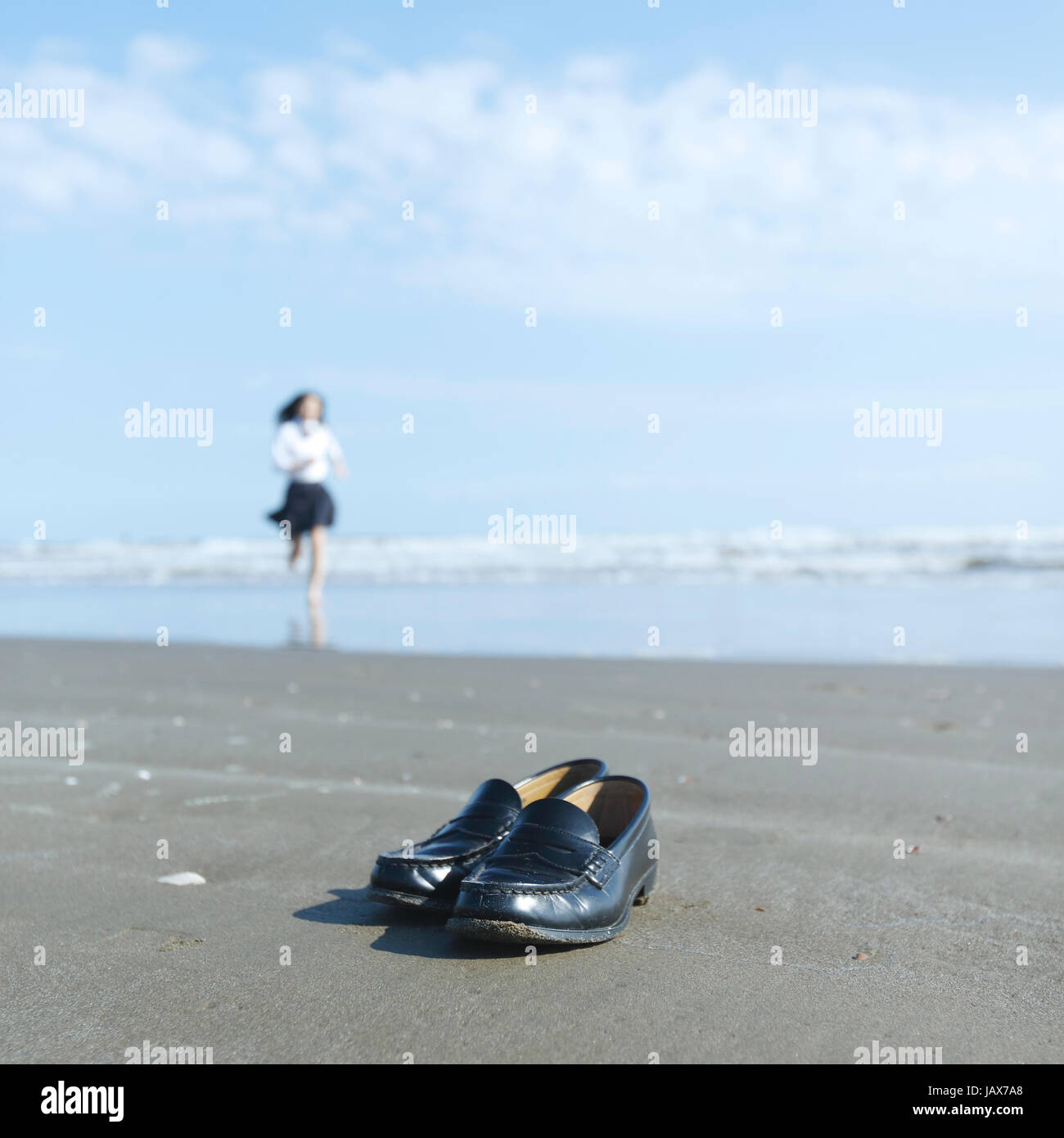 Young Japanese woman in a high school uniform running by the sea, Chiba, Japan Stock Photo