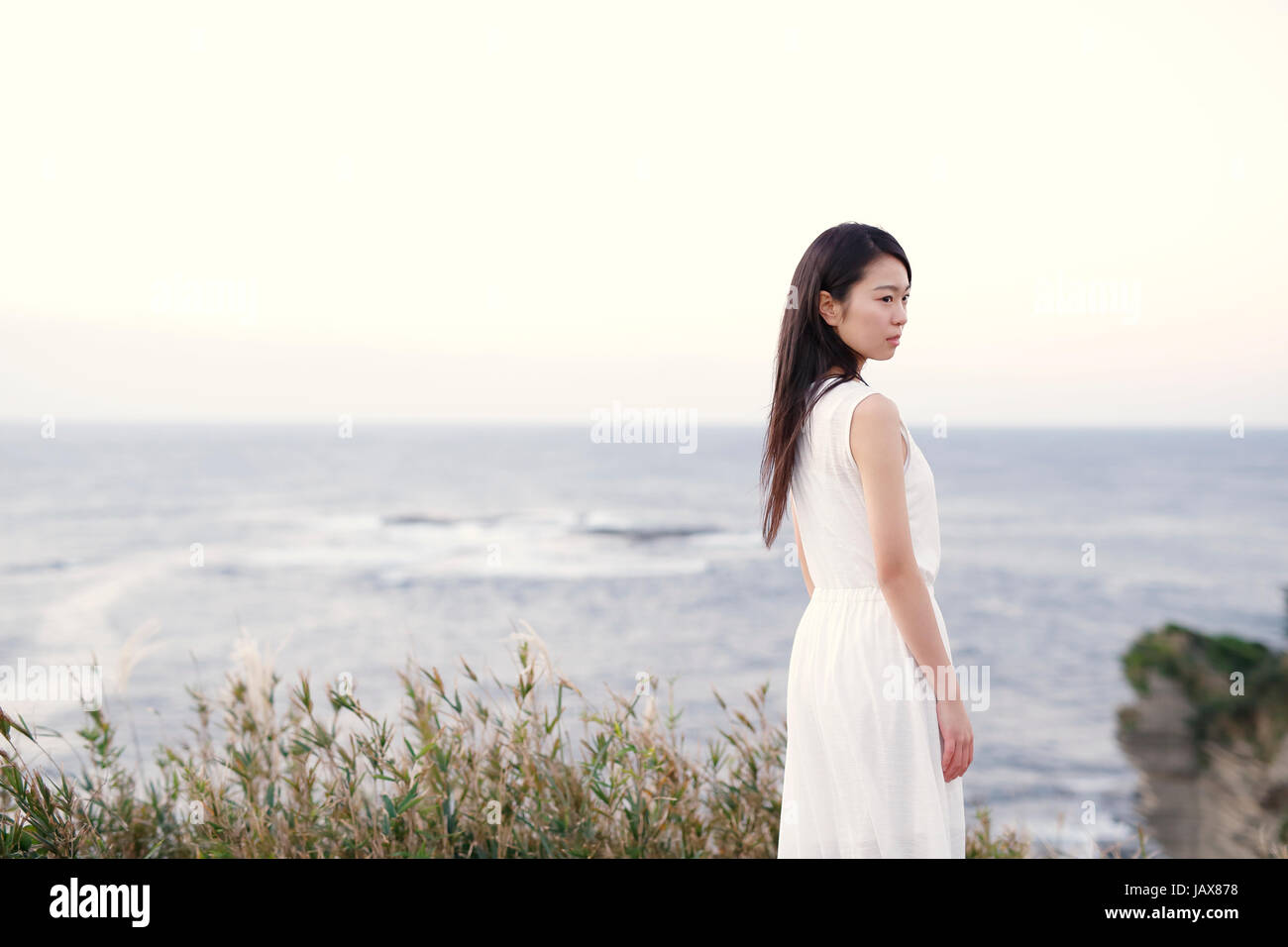 Young Japanese woman in a white dress at a cliff over the sea at ...