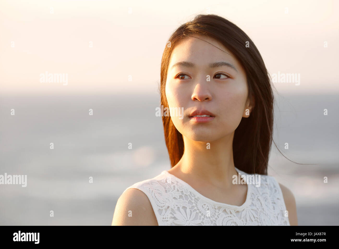 Young Japanese woman in a white dress at a cliff over the sea at ...