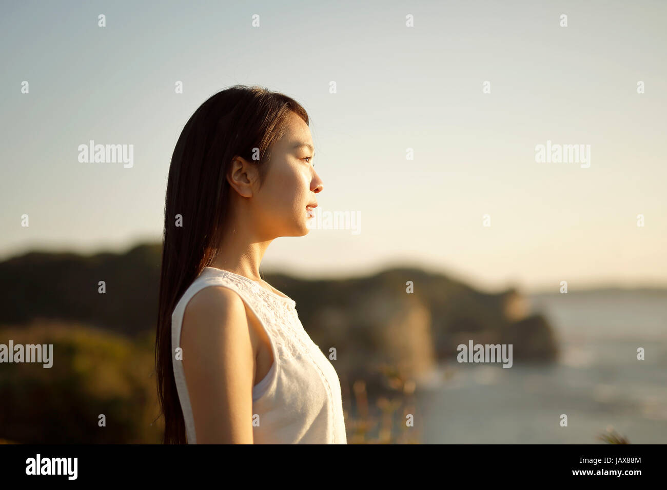Young Japanese woman in a white dress at a cliff over the sea at ...