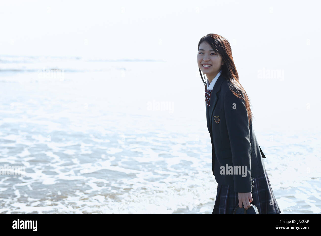 Young Japanese woman in a high school uniform by the sea, Chiba, Japan Stock Photo
