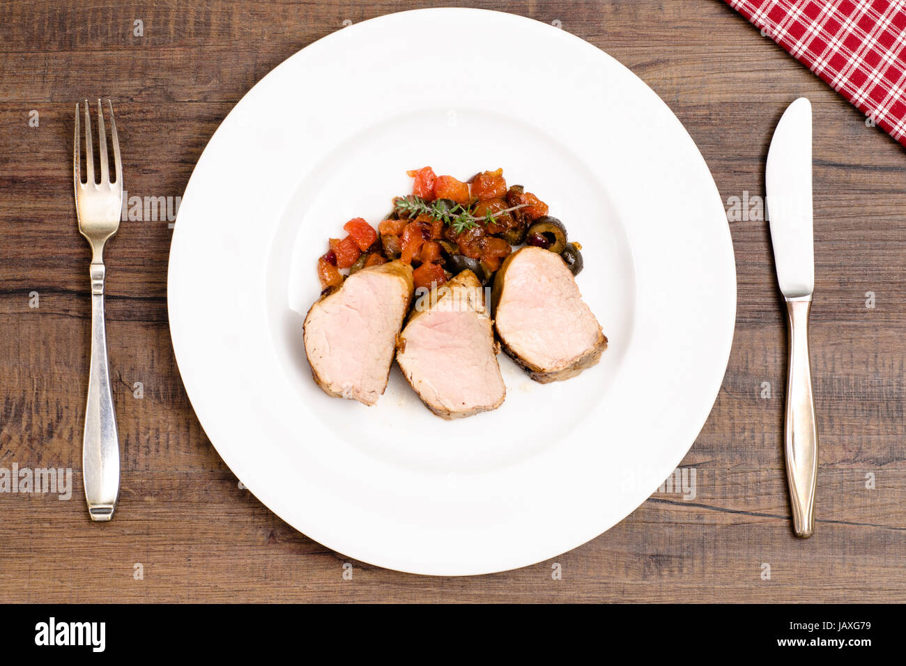 Gebratenes Schweinefilet auf einem Teller mit Tomaten und schwarzen ...