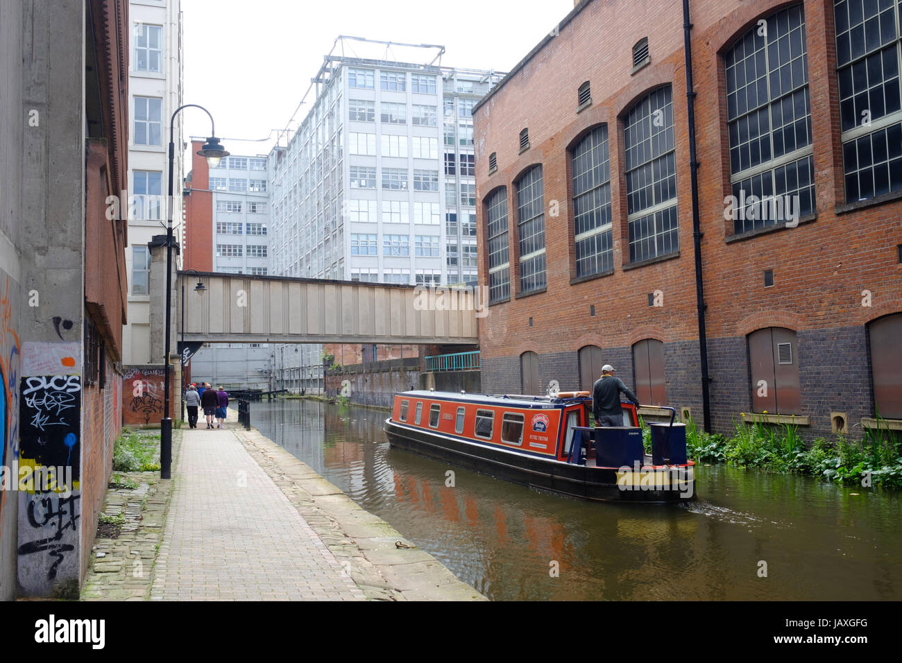 Barge passing though industrial units on Manchester Canal, city centre, Manchester, UK Stock Photo