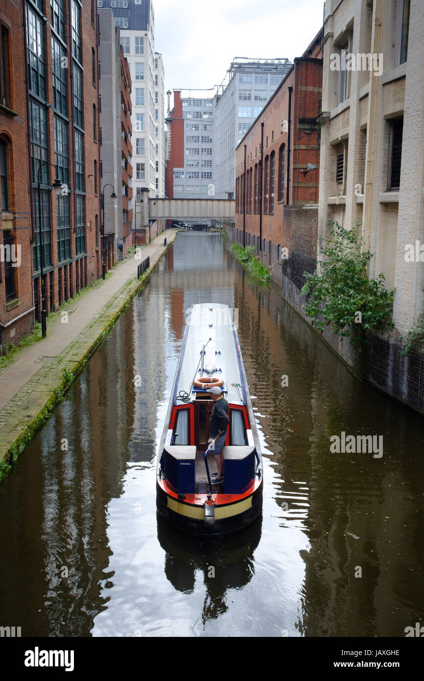 Barge on Manchester Canal, going between industrial buildings, city centre, Manchester, UK Stock Photo