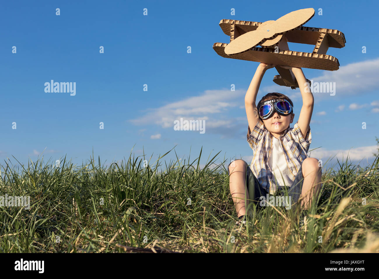 Little boy playing with cardboard toy airplane in the park at the day ...