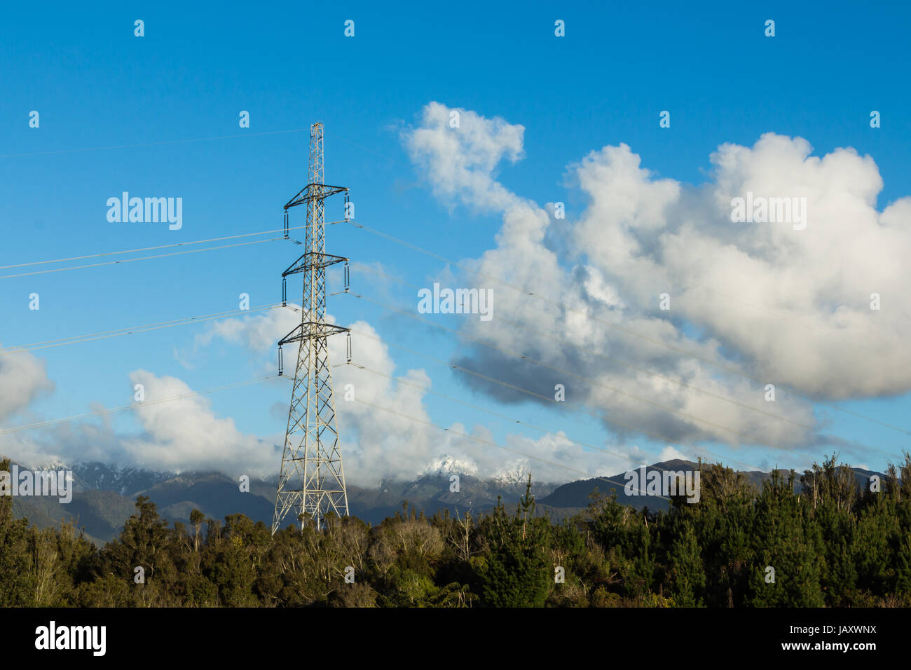 High voltage power line tower with snow top mountains in the background ...