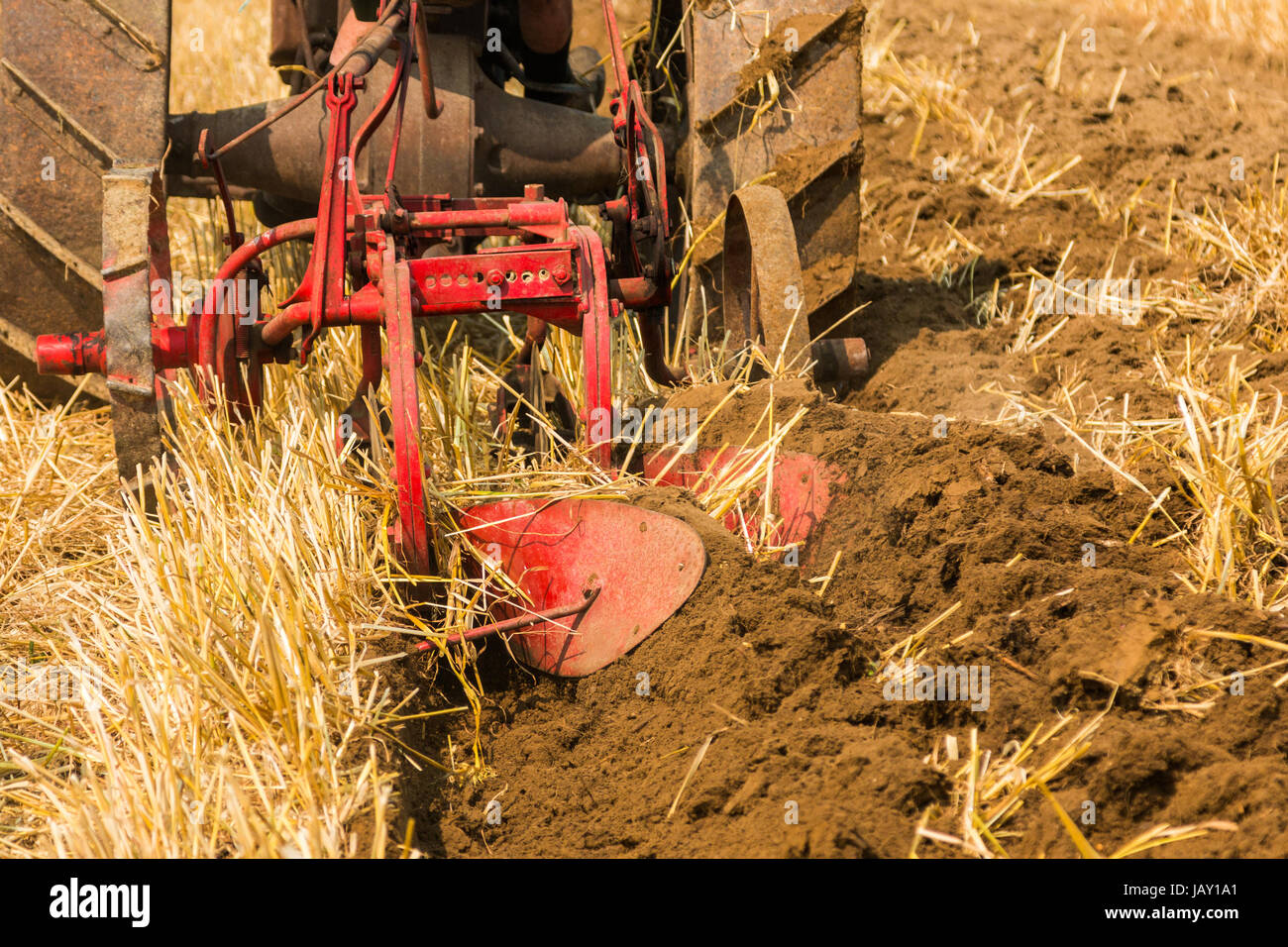 On vintage red plough turning over the soil. Stock Photo