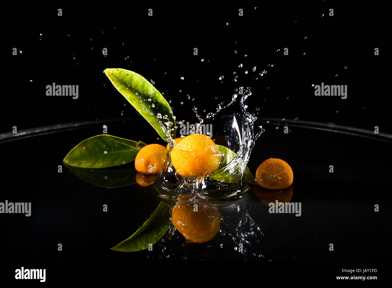citrus fruit falling in water drops splashing everywhere. Concept of freshness and purity. Stock Photo