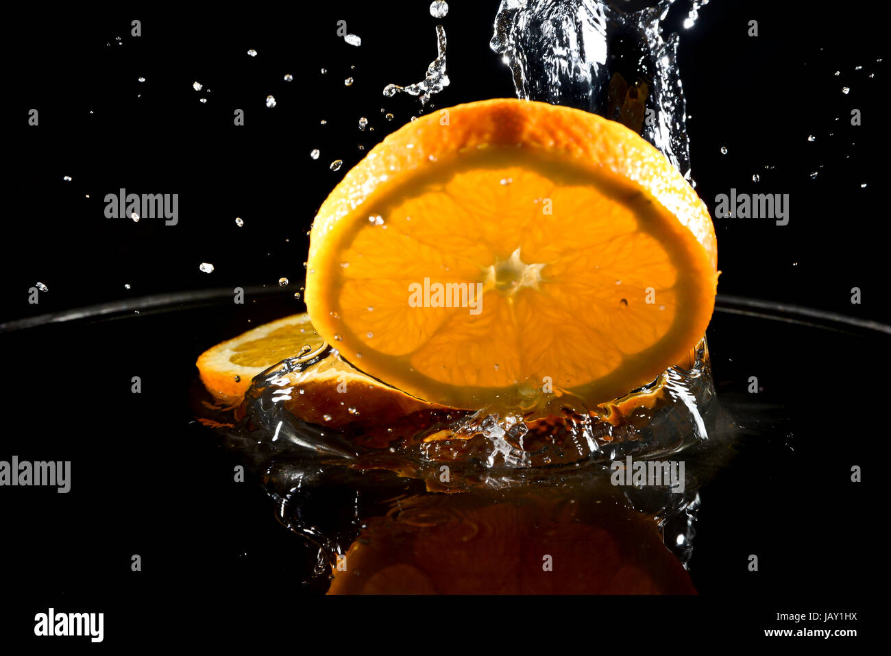 citrus fruit falling in water drops splashing everywhere. Concept of freshness and purity. Stock Photo