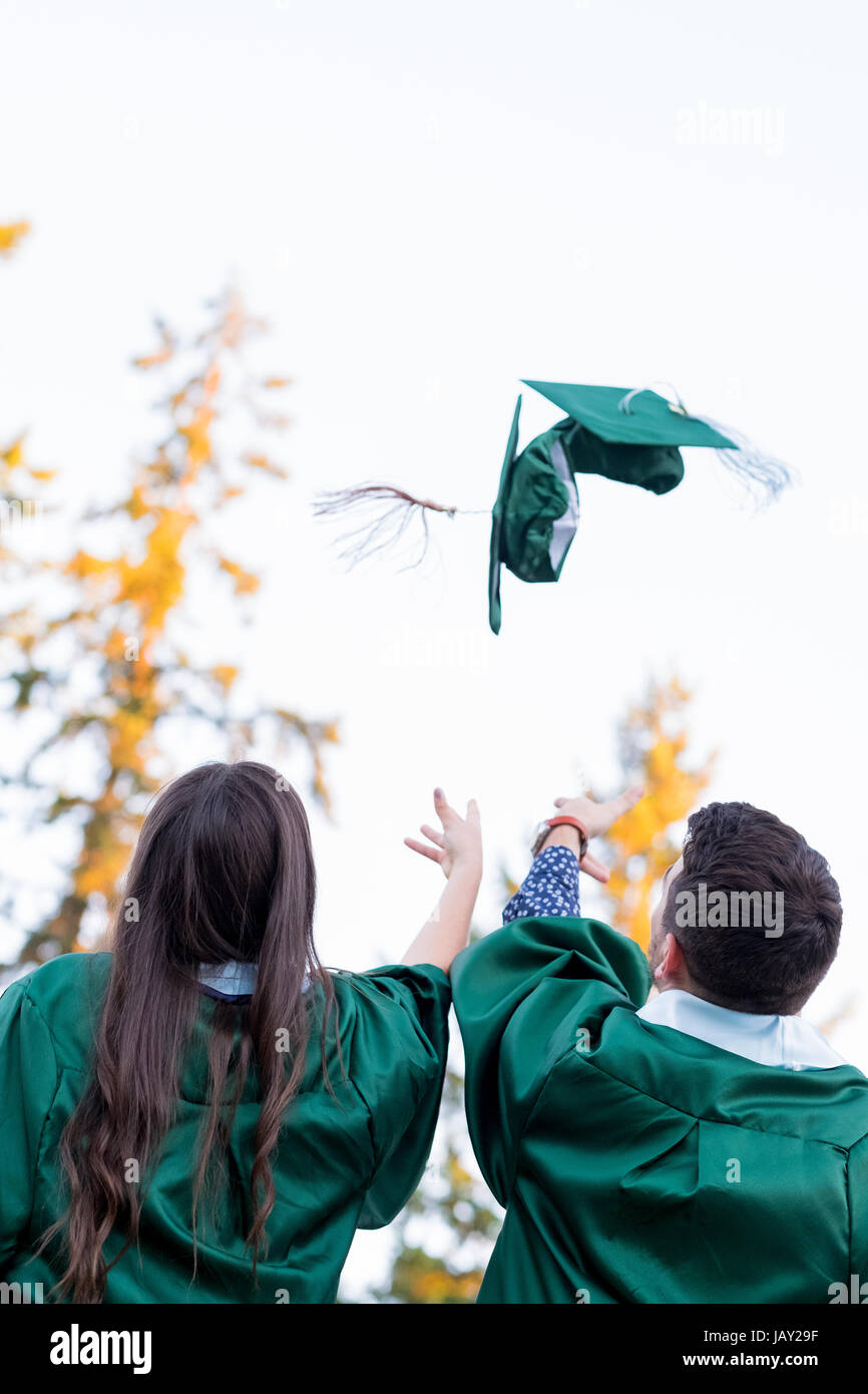 Two college students throw their caps in the air during graduation ceremonies at a university in