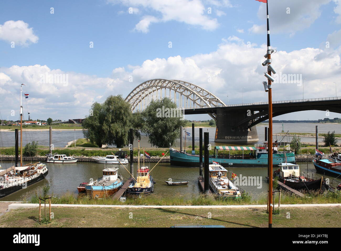 Waalbrug (1936), 600m long arch bridge over the Waal River in Nijmegen, Gelderland, Netherlands. Boats moored at Lindenberghaven harbour at Waalkade Stock Photo