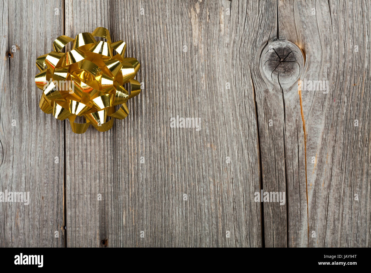 Weihnachtshintergrund mit goldener Geschenkschleife auf rustikalem Holzhintergrund Stock Photo