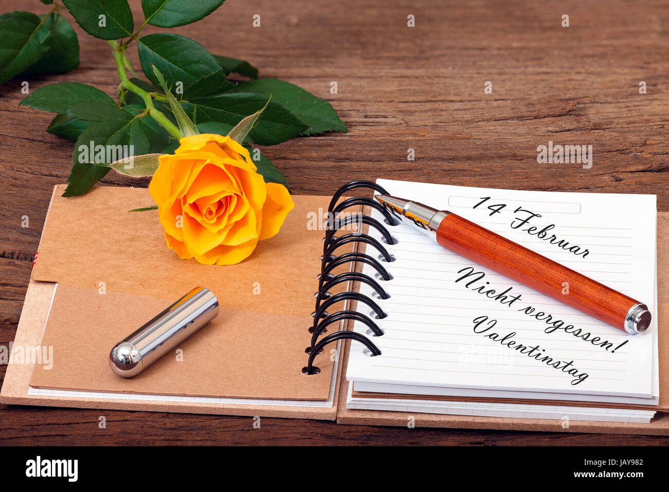 Notizbuch aufgeschlagen mit dem Text '14 Februar Nicht vergessen! Valentinstag' und ein Stift liegen auf hölzernen Untergrund Stock Photo