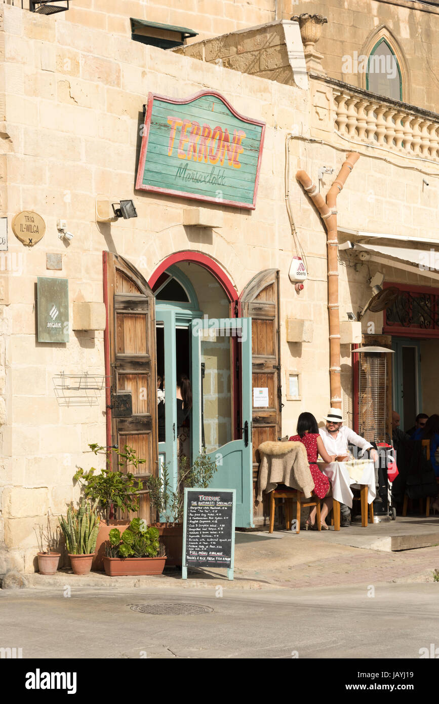 A man and woman sitting outside the restaurant Terrone in Marsaxlokk Malta in sunshine eating al fresco Stock Photo
