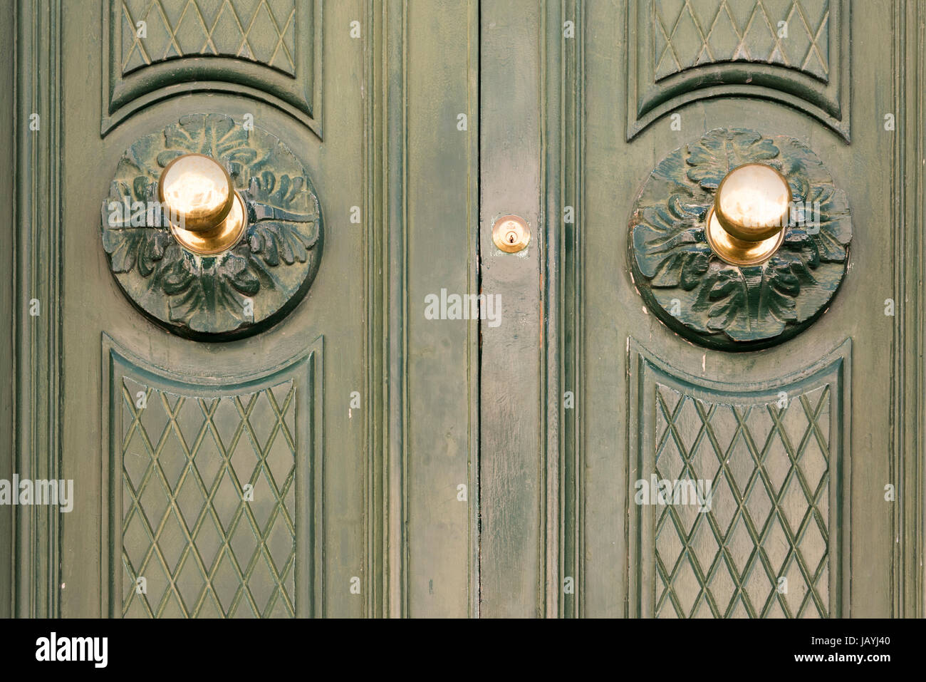 A Close Up Of Two Brass Door Handles On A Green Wooden Painted