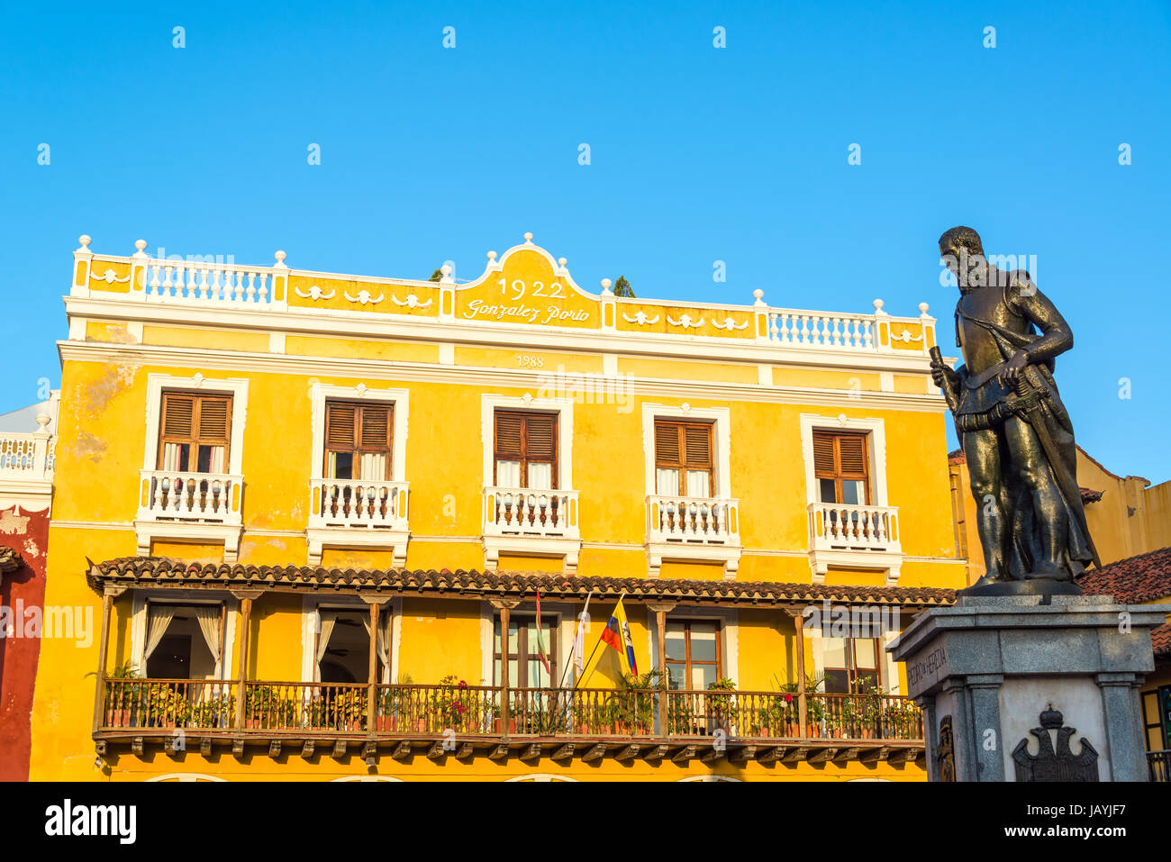 Yellow colonial building in Cartagena, Colombia with a statue of Pedro de Heredia, the founder of the city Stock Photo