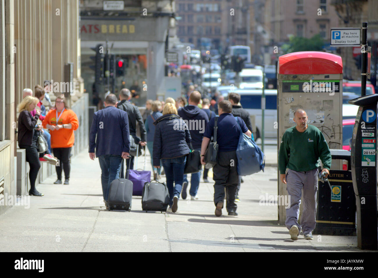 tourists in Glasgow Scotland walking on street towards station with bags Stock Photo