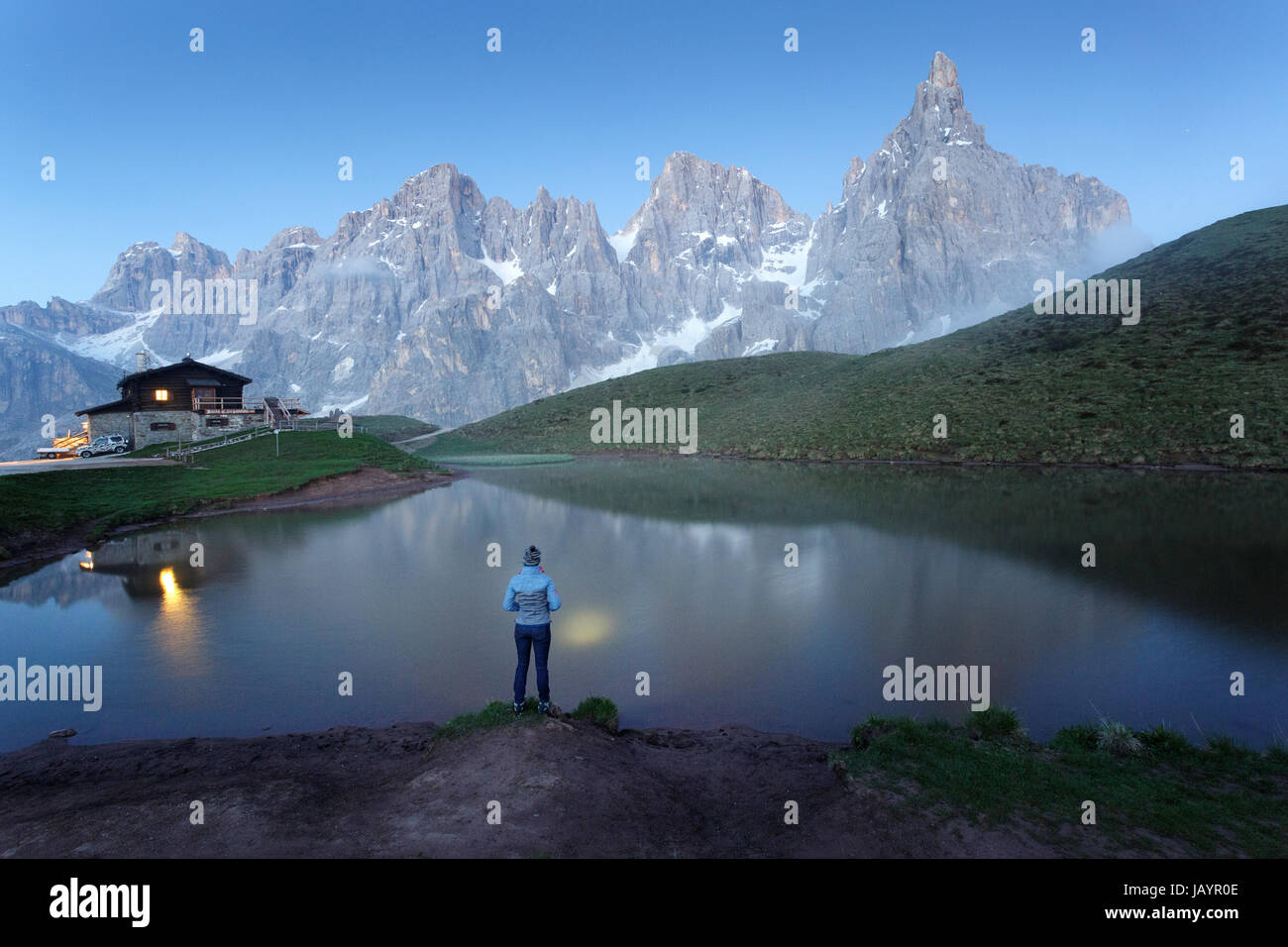 Woman standing at the lake at Rifugio Segantini with a head torch, Dolommites, Italy. Stock Photo