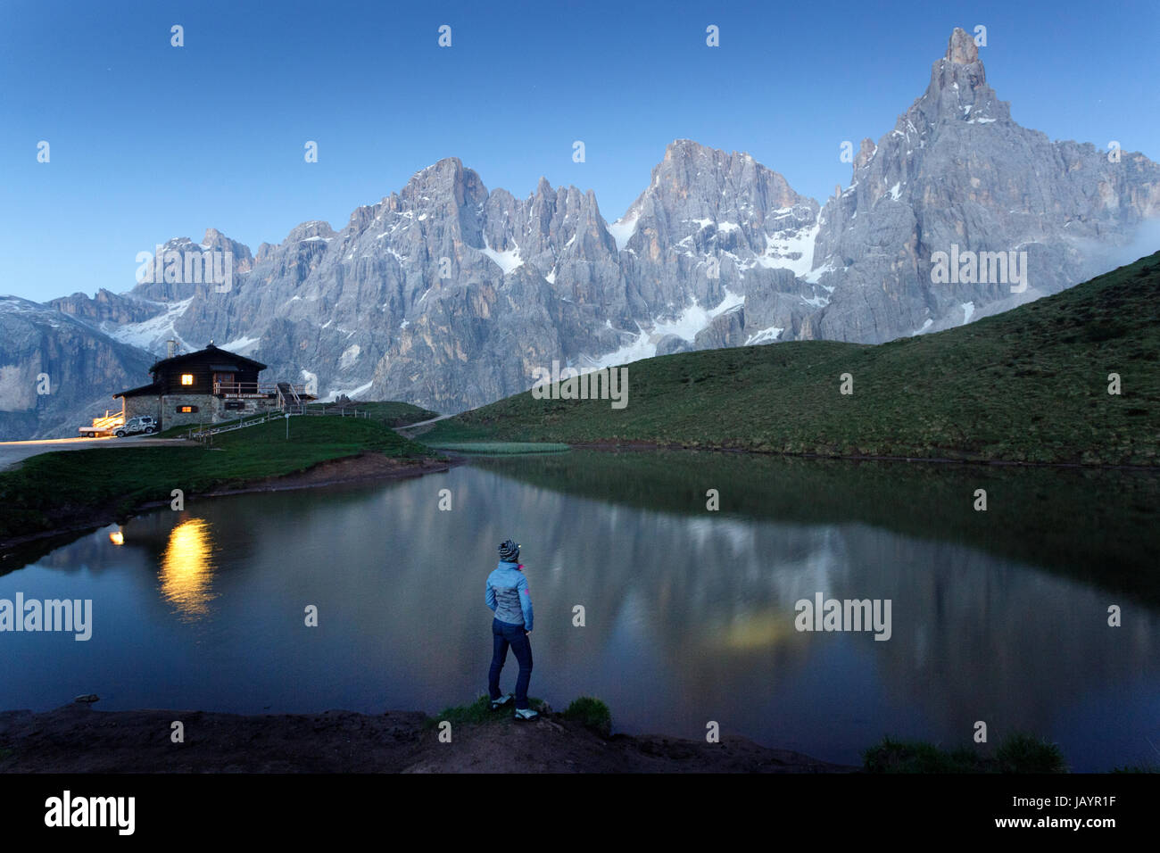 Woman standing at the lake at Rifugio Segantini with a head torch, Dolommites, Italy. Stock Photo