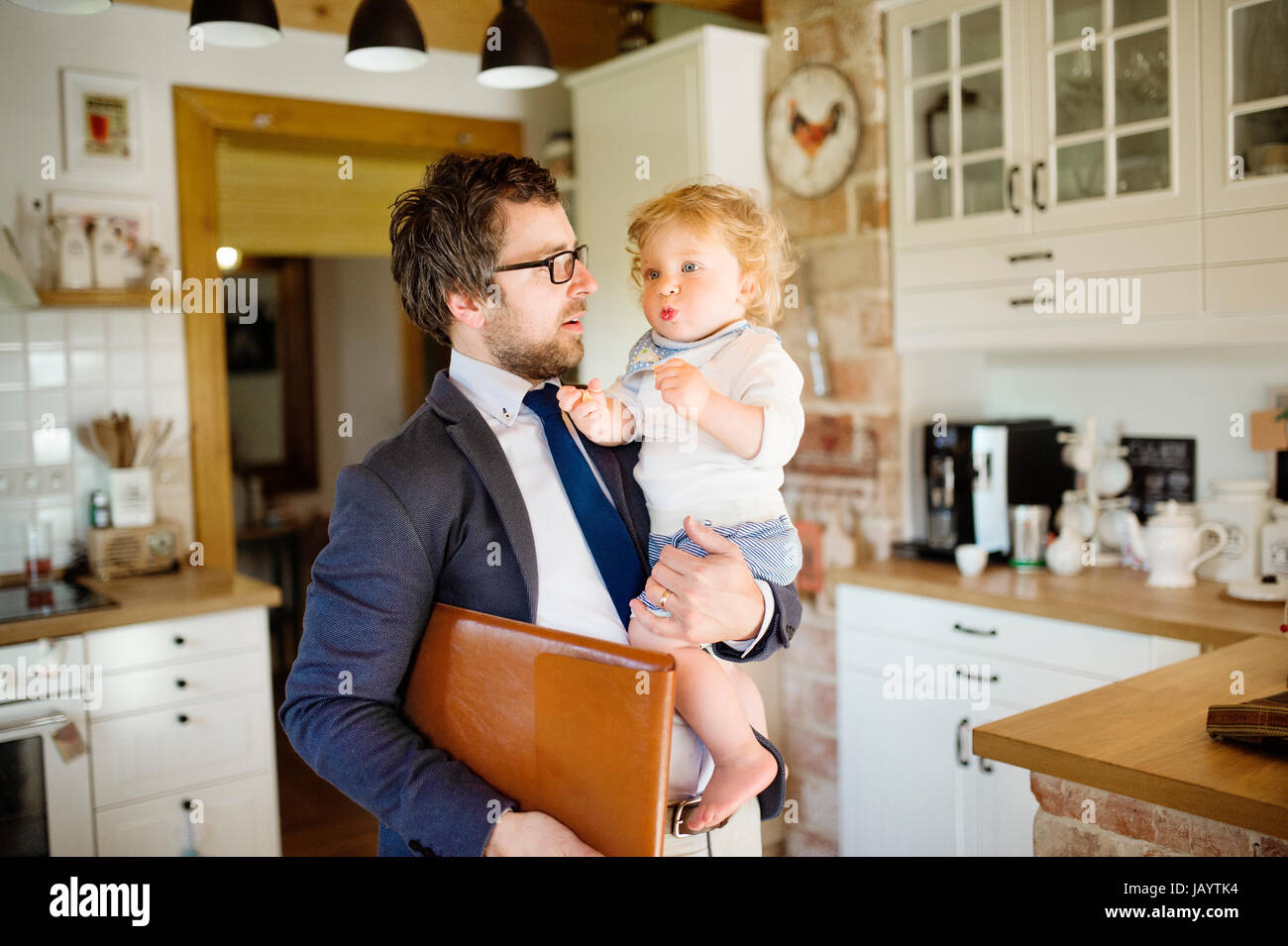 Businessman coming home, holding little son in the arms. Stock Photo
