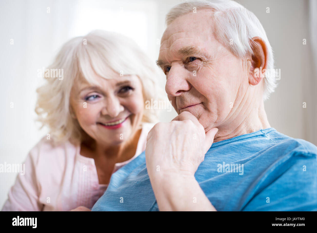 Happy senior couple relaxing together at home, man thinking Stock Photo