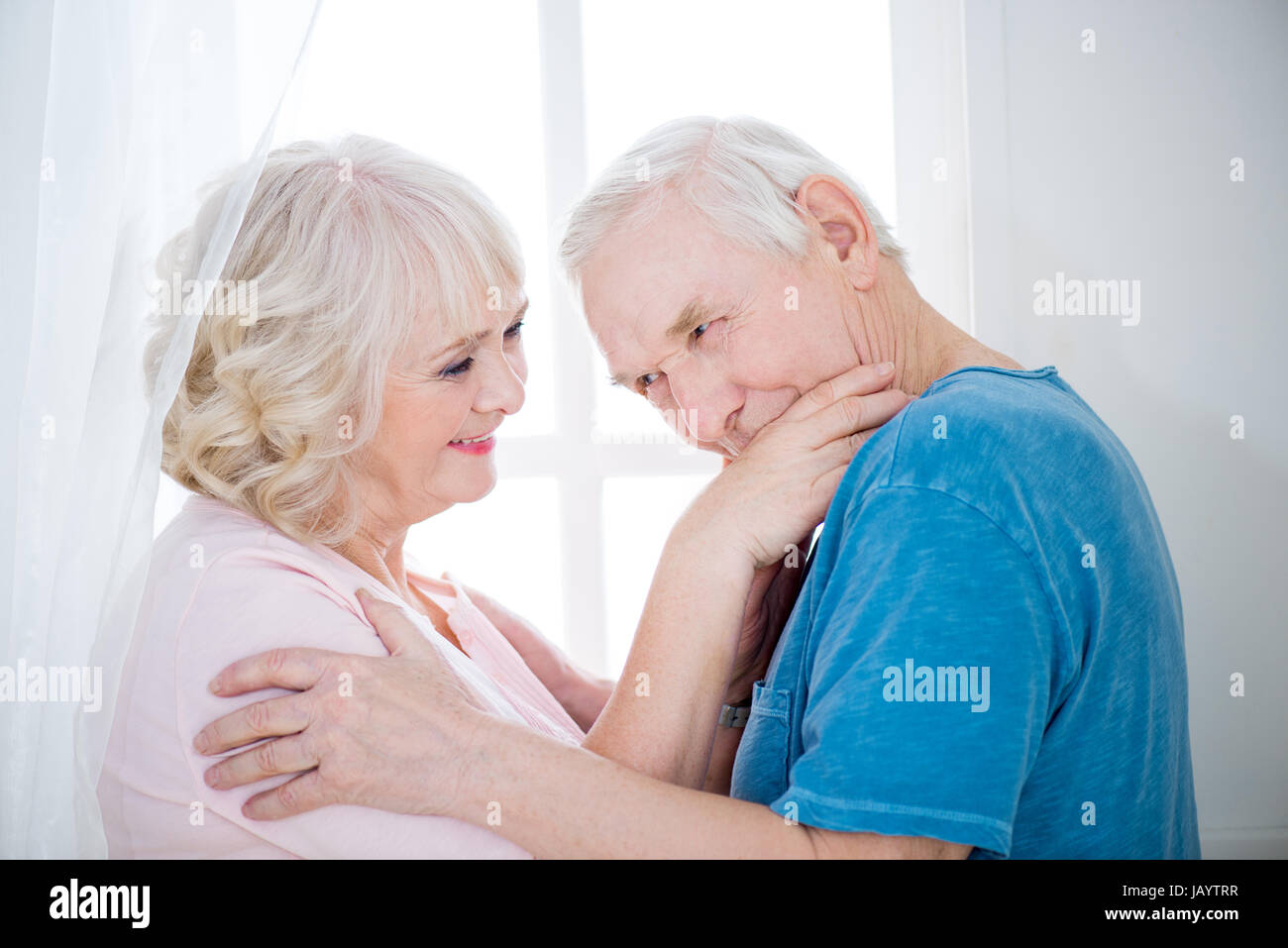 Portrait of happy senior couple hugging, man kissing hand. Stock Photo