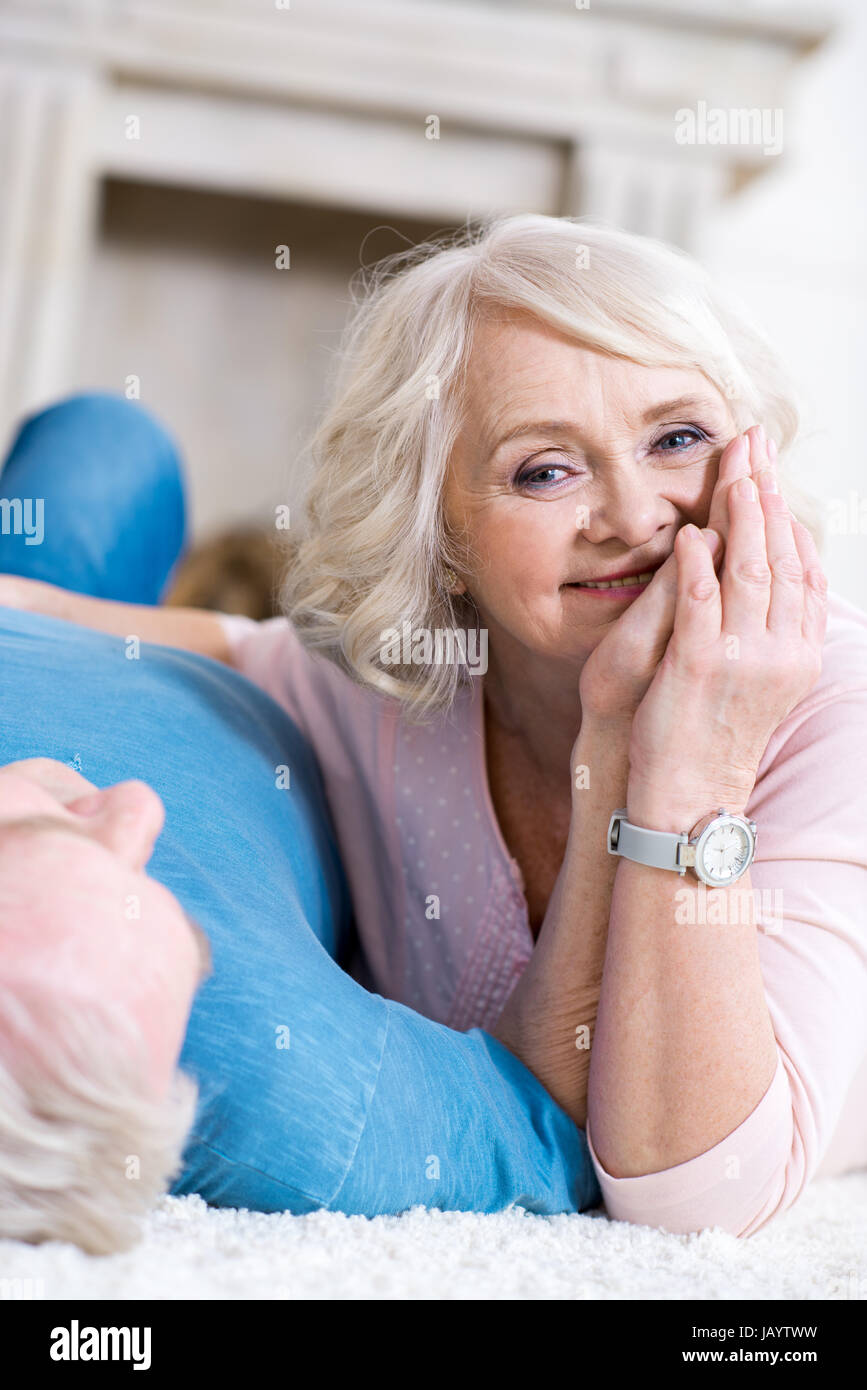 Happy senior couple lying together on carpet and hugging Stock Photo