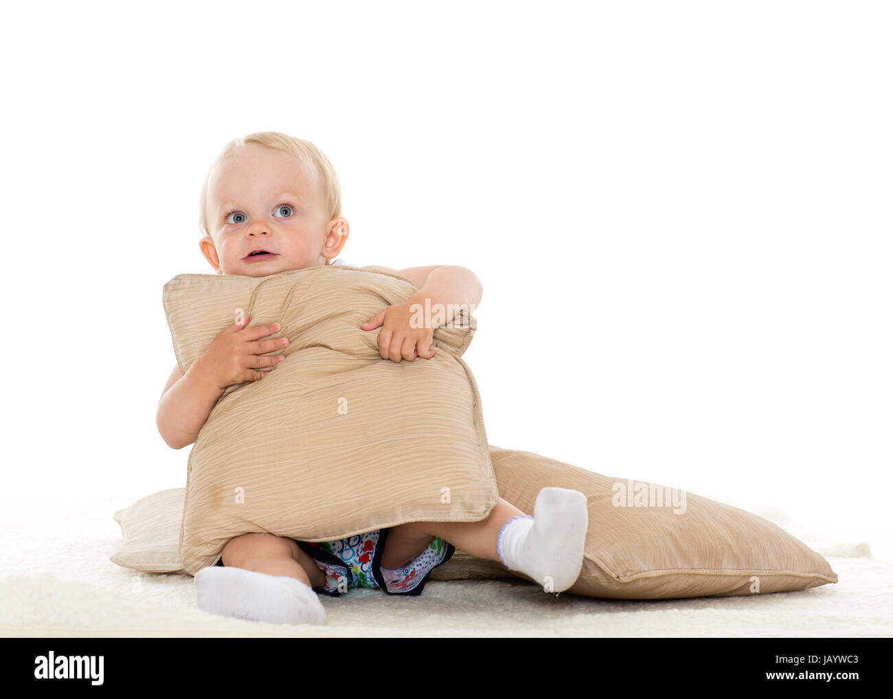 Sweet Small Baby Is Playing With Pillows On A White Background