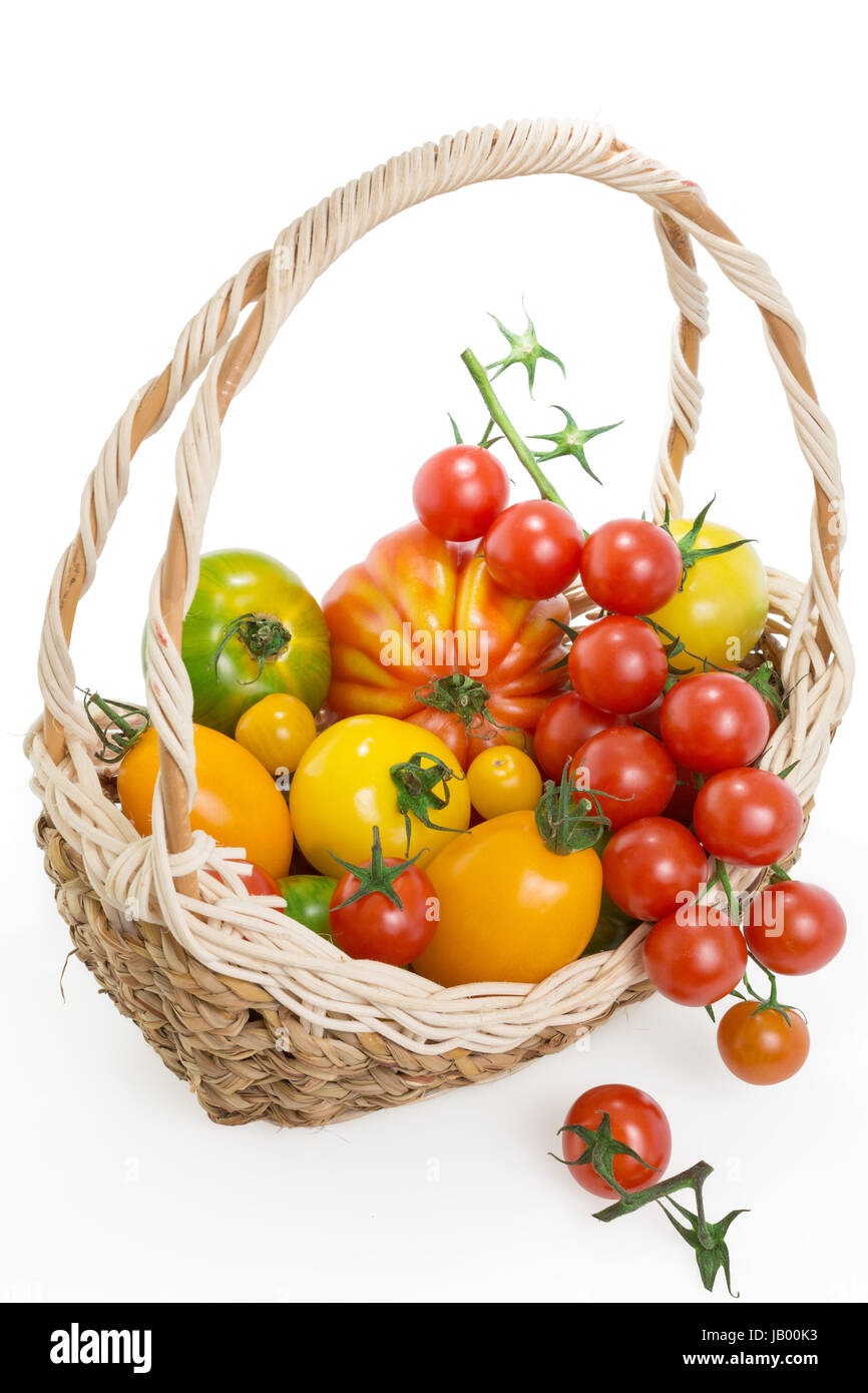 Variety of fresh colorful tomatoes in a basket , isolated on white ...