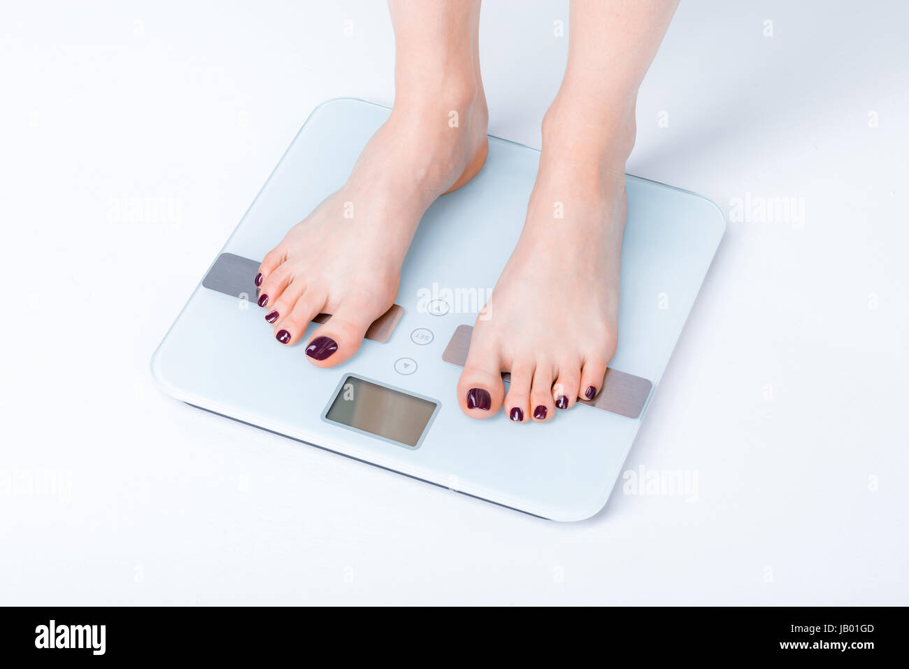 A woman standing on a weight scale Stock Photo - Alamy