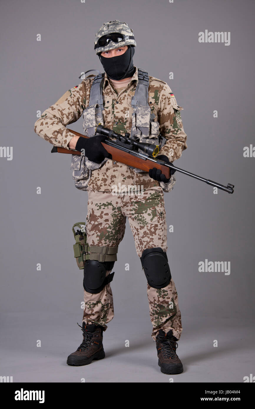 Soldier with sniper rifle posing over grey background Stock Photo - Alamy