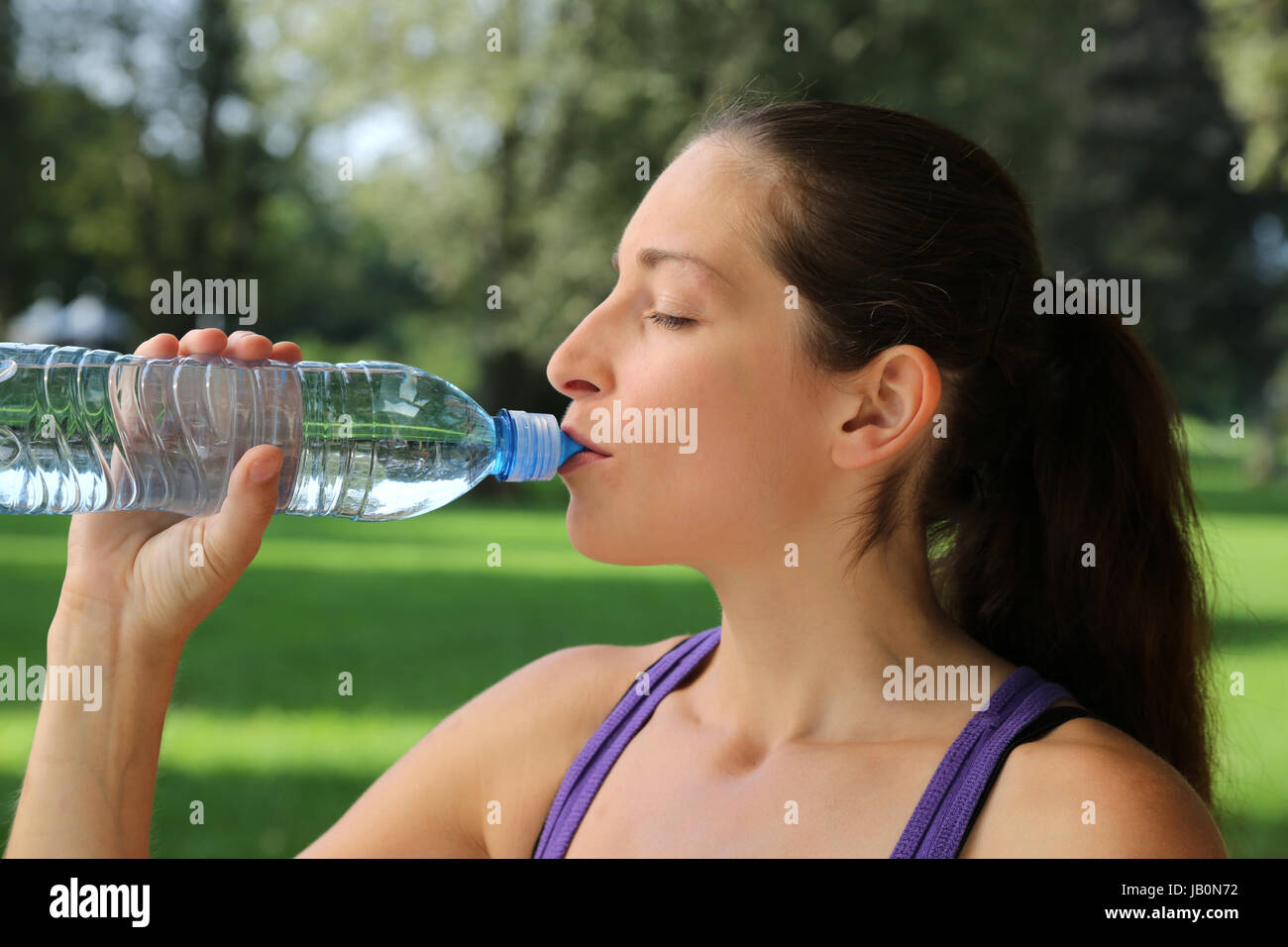 Eine sportliche Frau trinkt Wasser aus einer Flasche beim Sport oder Joggen Stock Photo