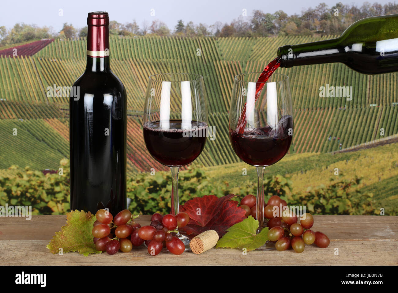 Rotwein wird aus einer Weinflasche in ein Weinglas eingegossen Stock Photo