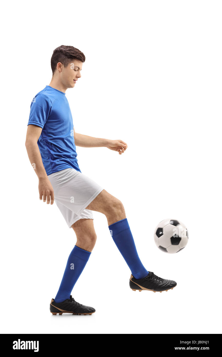 Full length profile shot of a teenage soccer player juggling a football